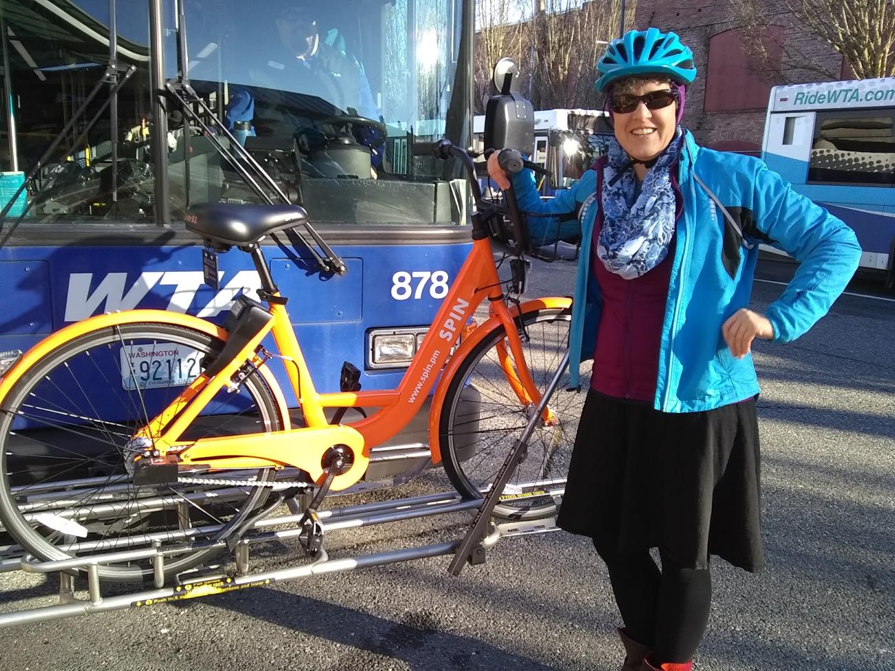 Jillian poses with a Spin bike on the front of a WTA bus