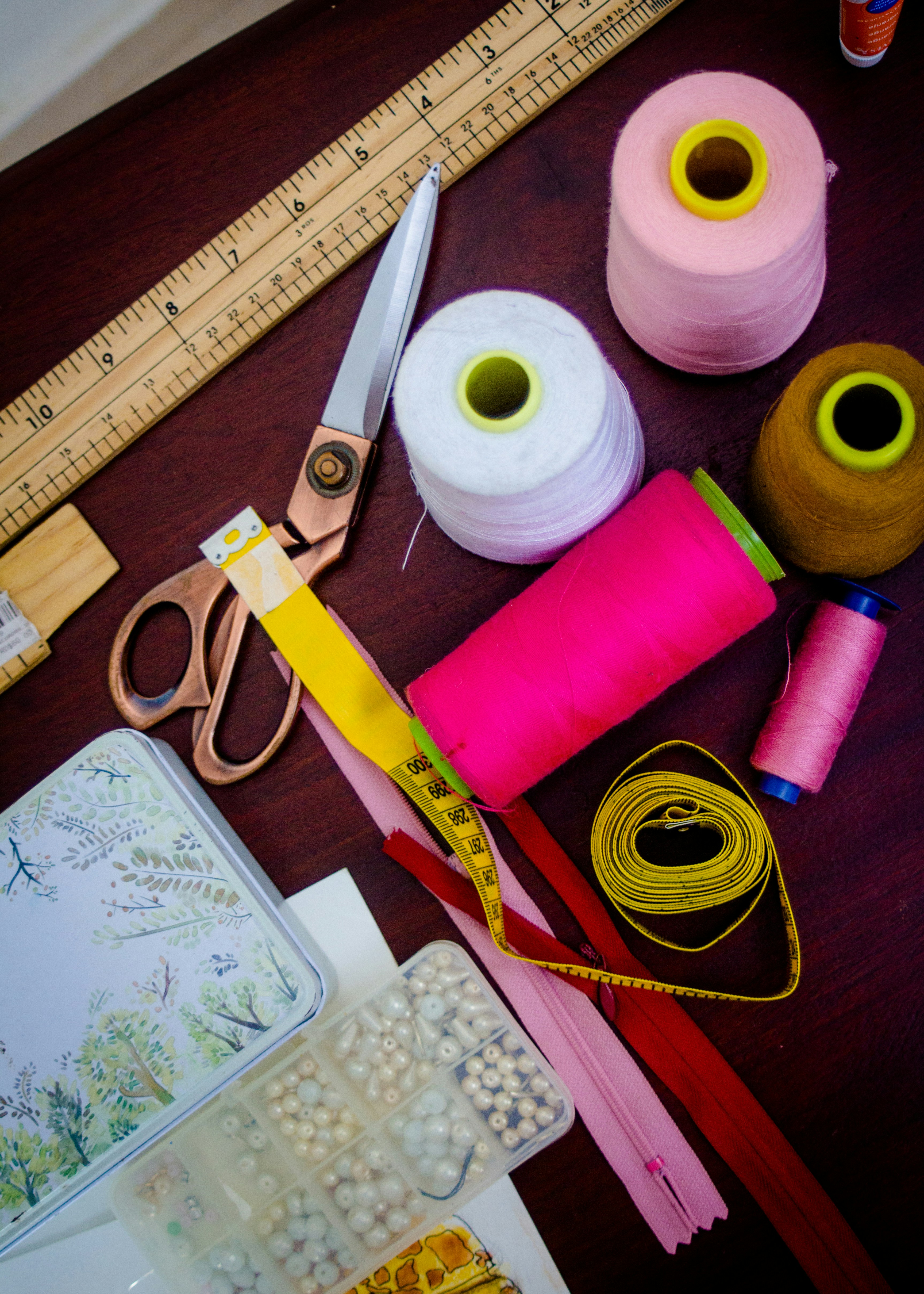  The image shows sewing threads, scissors, measuring tape, and a zipper laid out on a table.